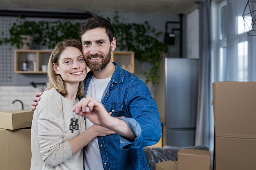 A young couple with keys moving into a new home