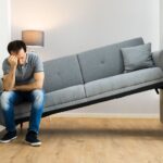 man sitting on a couch that doesn't fit in his room