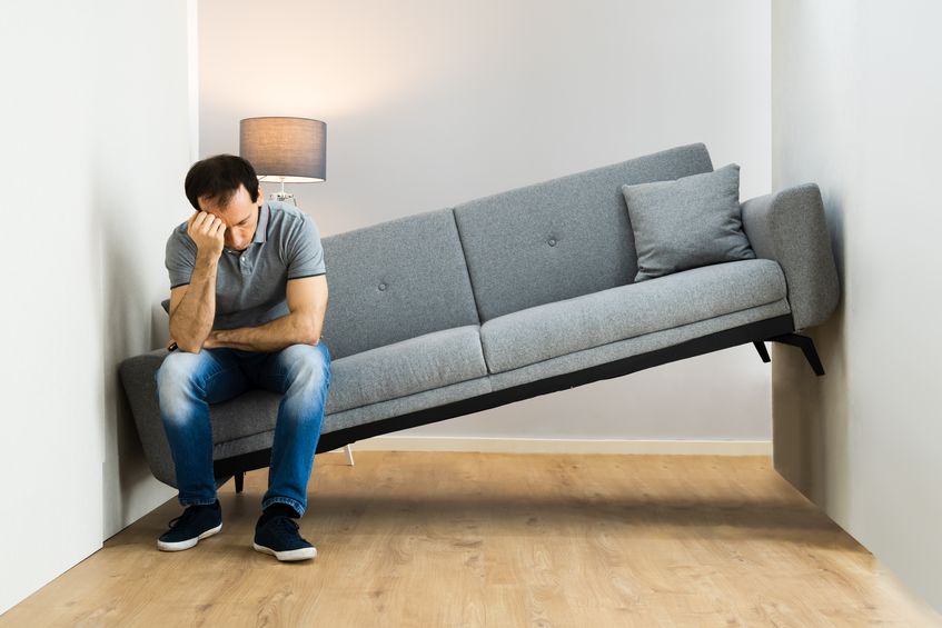man sitting on a couch that doesn't fit in his room