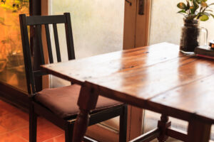 rustic wooden table and chairs with warm natural light setting illuminated through door glass window. Indoor decoration, interior design, architecture, house furniture, home cafe and living concept